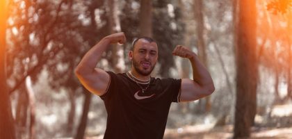 a man flexing his muscles in the woods