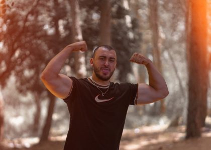 a man flexing his muscles in the woods